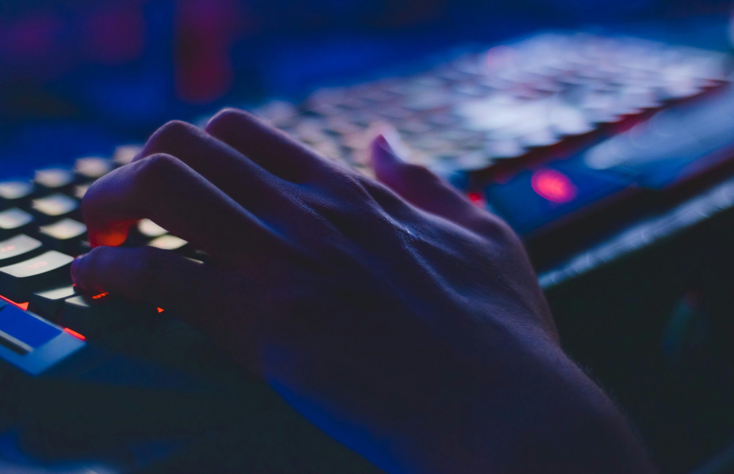 A hand typing on a glowing keyboard in dim lighting, perfect for tech themes.